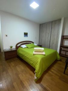 a bedroom with a green bed with towels on it at DEPARTAMENTO en La Paz MUNDO LUNA in La Paz