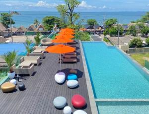 a swimming pool with umbrellas and chairs next to a pool at The Poem Hotel in Mae Pim
