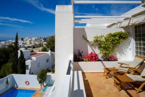 a balcony with chairs and a swimming pool on a house at miKasa Agua Amarga & SPA in Agua Amarga
