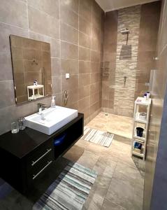 een badkamer met een wastafel en een douche met een spiegel bij Waterfront Townhouse in Bijilo