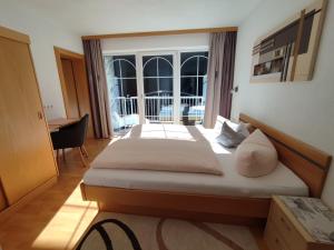 een slaapkamer met 2 bedden en een groot raam bij Apart Bella Cascata in Kappl