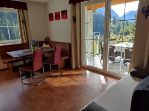 een eetkamer met een tafel en stoelen en een balkon bij Apart Bella Cascata in Kappl