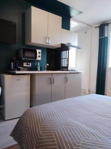 uma cozinha com armários brancos e uma cama num quarto em Studio et chambres d'hôtes les nuits de Gesnes em Saint-Germain-du-Corbéis