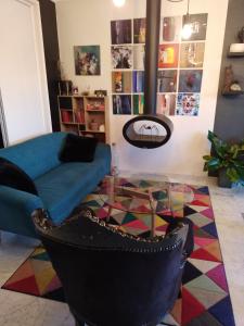 un salon avec un canapé bleu et une table en verre dans l'établissement Studio et chambres d'hôtes les nuits de Gesnes, à Saint-Germain-du-Corbéis