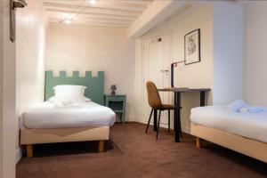 a bedroom with two beds and a desk with a chair at Hotel Le Dauphin in Honfleur