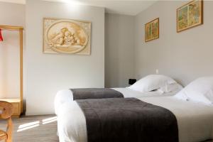 two beds in a room with white walls at Hotel Le Dauphin in Honfleur