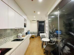 une cuisine avec des armoires blanches et une table et des chaises dans l'établissement Gavi Home - Luxury Apartment Vinhome Green Bay Mễ Trì Hà Nội, à Hanoï 12 autres photos