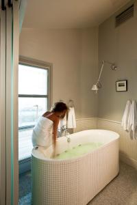a woman standing in a bath tub in a bathroom at The Majestic Hotel in Fira