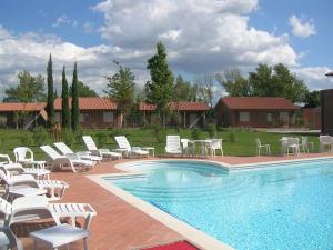 uma piscina com cadeiras brancas e cadeiras ao lado de uma casa em Residence San Rossore em Pisa