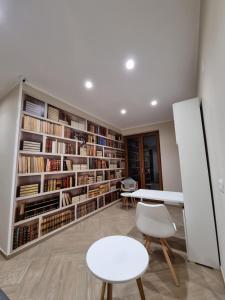 eine Bibliothek mit weißen Stühlen, einem Tisch und Bücherregalen in der Unterkunft Nonno Umberto Apartments in Pompei