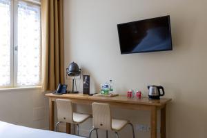 a room with a desk with two chairs and a television at Hotel Le Dauphin in Honfleur