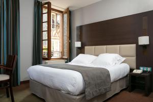 a bedroom with a large bed and a window at Hotel Le Dauphin in Honfleur