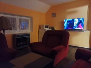 a living room with a chair and a flat screen tv at MotoHostel Wolter - apartmán Leme in Všeň