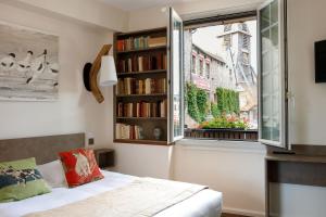 a bedroom with a bed and a window with books at Hotel Le Dauphin in Honfleur