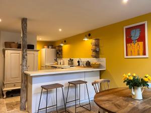 a kitchen with yellow walls and a table and chairs at Maison Père in Lagarde