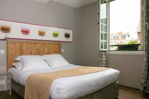 a bedroom with a large bed with a large window at Hotel Le Dauphin in Honfleur