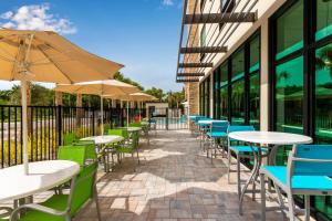 a row of tables and chairs with umbrellas outside a building at Holiday Inn Express & Suites Ft Myers Beach-Sanibel Gateway by IHG in Fort Myers Beach