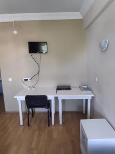 a white desk with a chair and a tv on a wall at Aziziye Hotel in Konya