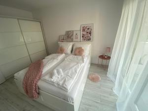 um quarto com uma cama com lençóis brancos e animais de peluche em Apartament Nice Stay em Lubin