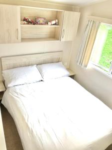 a white bed in a small room with a window at NB12 Entire Caravan - Newquay in Newquay Bay Resort