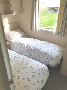 two twin beds in a room with a window at NB12 Entire Caravan - Newquay in Newquay Bay Resort
