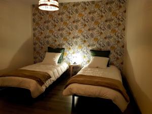 2 Einzelbetten in einem Zimmer mit einer Wand in der Unterkunft Le Petit Relais de Launois in Launois-sur-Vence