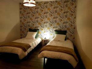 two twin beds in a room with a wall at Le Petit Relais de Launois in Launois-sur-Vence