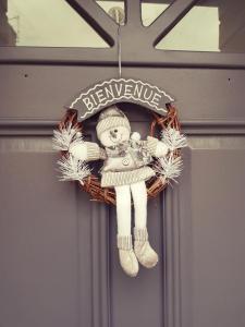 einen Weihnachtskranz mit einer Puppe an der Tür in der Unterkunft Le Petit Relais de Launois in Launois-sur-Vence