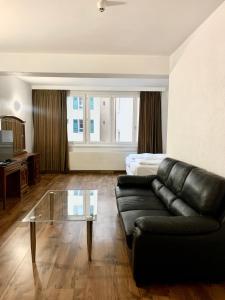 ein Wohnzimmer mit einem schwarzen Ledersofa und einem Glastisch in der Unterkunft Hotel Balzac in Genf