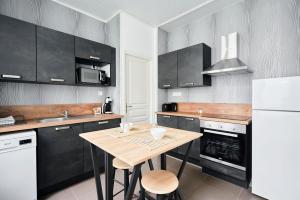 une cuisine avec une table en bois et des armoires noires dans l'établissement Locations Boulogne sur mer, 2 personnes, Les Oyats, à Boulogne-sur-Mer 17 autres photos