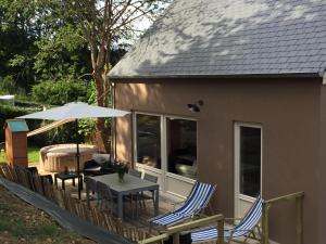 eine Terrasse mit einem Tisch, Stühlen und einem Sonnenschirm in der Unterkunft Le Clos de Jabanelle in Ciney