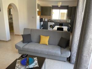 a living room with a gray couch and a kitchen at Sirena Sunrise 120 in Paphos