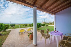 a patio with a table and chairs and a view of the ocean at Beachside Bungalows Acharavi Corfu in Acharavi