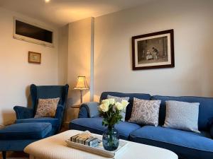 a living room with blue couches and a vase of flowers at Maison Père in Lagarde