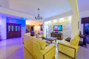 sala de estar con sofás amarillos y TV en Amani Villa en Protaras