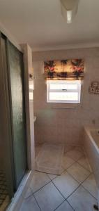 ein Bad mit einer Dusche, einer Badewanne und einem Fenster in der Unterkunft Hinterheim in Lambertʼs Bay