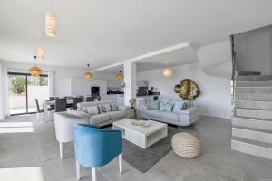 a living room with white furniture and a kitchen at Villa neuve et luxueuse vue mer proche Portovecchio in Zonza