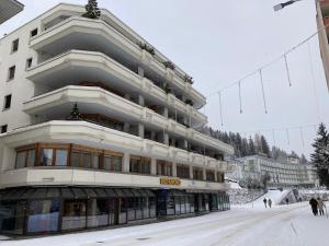 a large building with people walking in the snow at Your Pied-à-terre in Davos in Davos