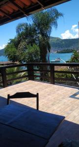 uma mesa e cadeira num deque com vista para a água em Lindo Apartamento com vista para o Mar - Mirante do Américo! em Angra dos Reis