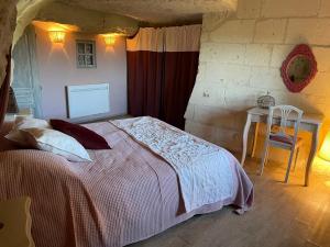 una camera con letto e tavolo con sedia di L’escale Troglo au bord de la Loire a Souzay-Champigny