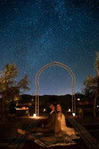 a couple sitting under an arch under a starry sky at Sahara Majestic Luxury Camp in Merzouga