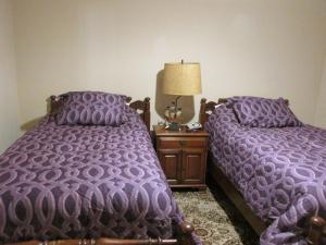 two beds in a bedroom with purple comforter at Cayce Charm Minutes to Downtown Columbia in Cayce