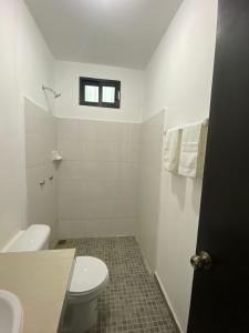 La salle de bains blanche est pourvue de toilettes et d'une fenêtre. dans l'établissement Hotel La Isla, à Cunduacán