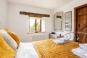 a bedroom with a bed and a window and a mirror at Granary Cottage - Luxury Barn Conversion in Weston Subedge