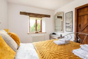 Schlafzimmer mit einem Bett, einem Fenster und einem Spiegel in der Unterkunft Granary Cottage - Luxury Barn Conversion in Weston Subedge