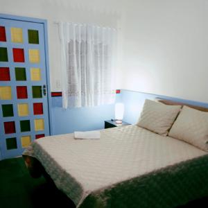 1 dormitorio con 1 cama con lámpara y ventana en Pousada Videira de Teresópolis, en Teresópolis
