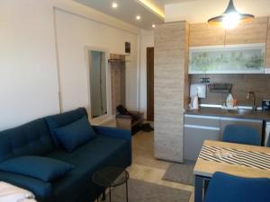 Una sala de estar con un sofá azul y una cocina. en Okili apartman S11 Milmari resort Kopaonik, en Kopaonik
