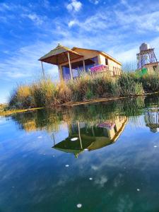 a house on an island in a body of water at Uros Quechua`s Lodge Titicaca in Puno