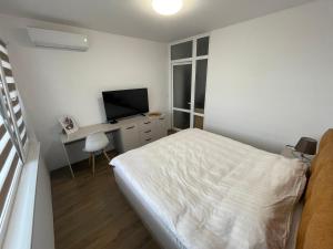 a bedroom with a bed and a desk with a television at DeTY's Apartment in Burgas