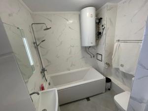 a white bathroom with a bath tub and a toilet at DeTY's Apartment in Burgas City